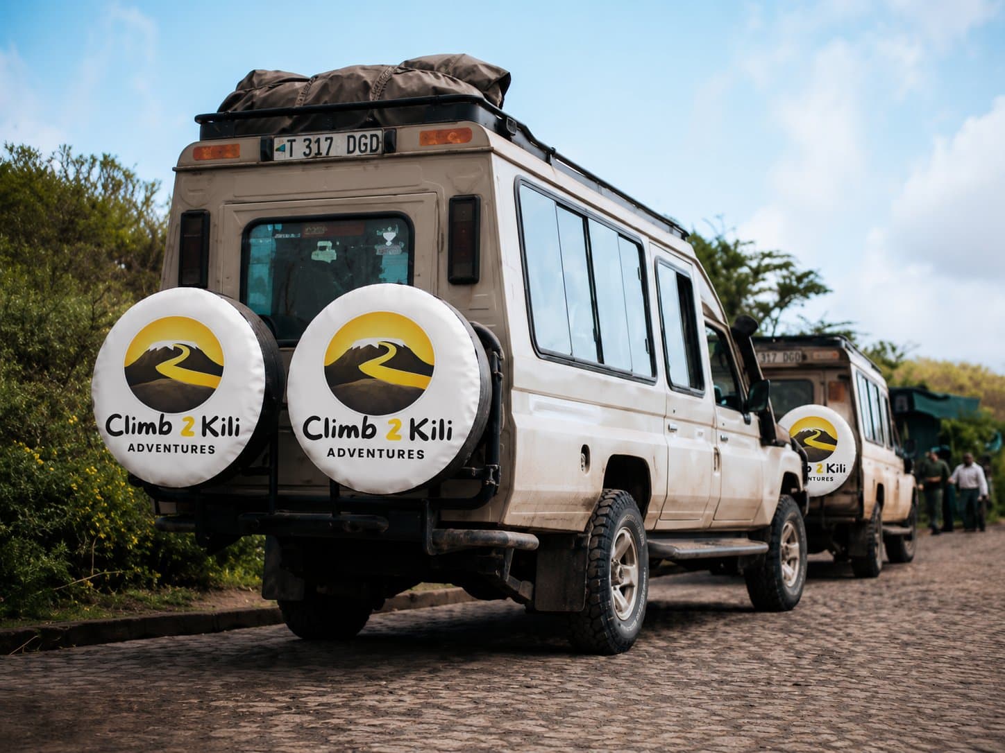Fondatore in piedi con guide Kilimanjaro, portatori, chef, piloti e membri della comunità locale sotto il Monte Kilimanjaro